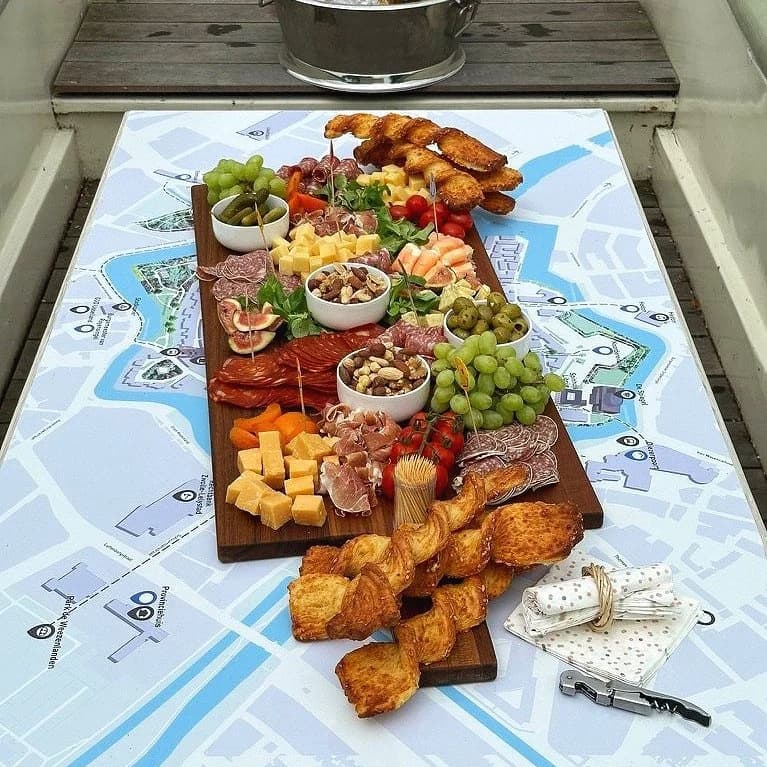 Reich gefüllte Häppchenplatte mit Käse und Aufschnitt auf dem Stadtplan-Tisch an Bord
