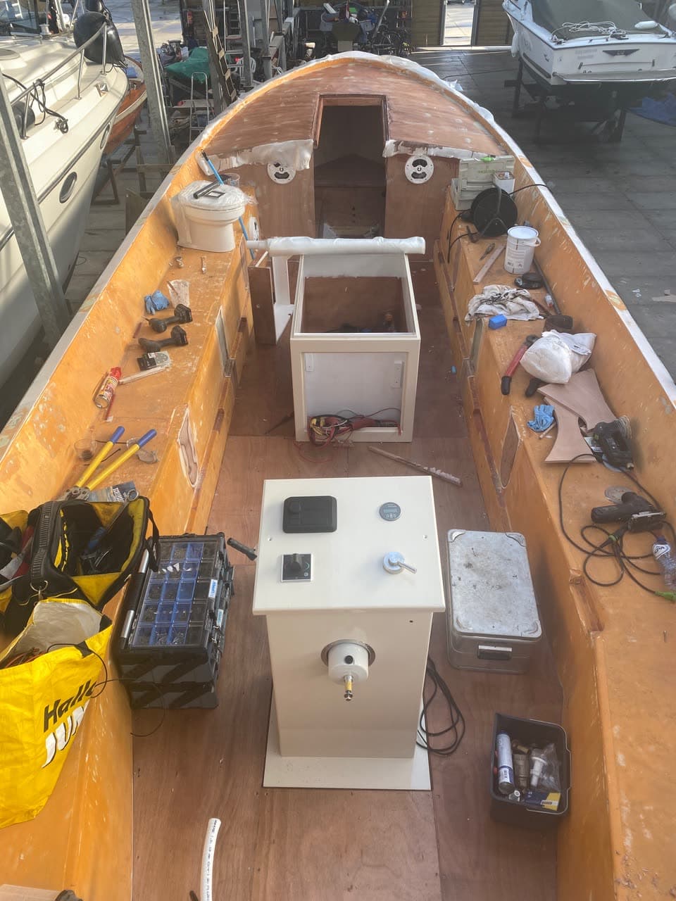 De nieuwe stuurconsole staat in de romp tijdens de ombouw, met bedieningspanelen en kabels
