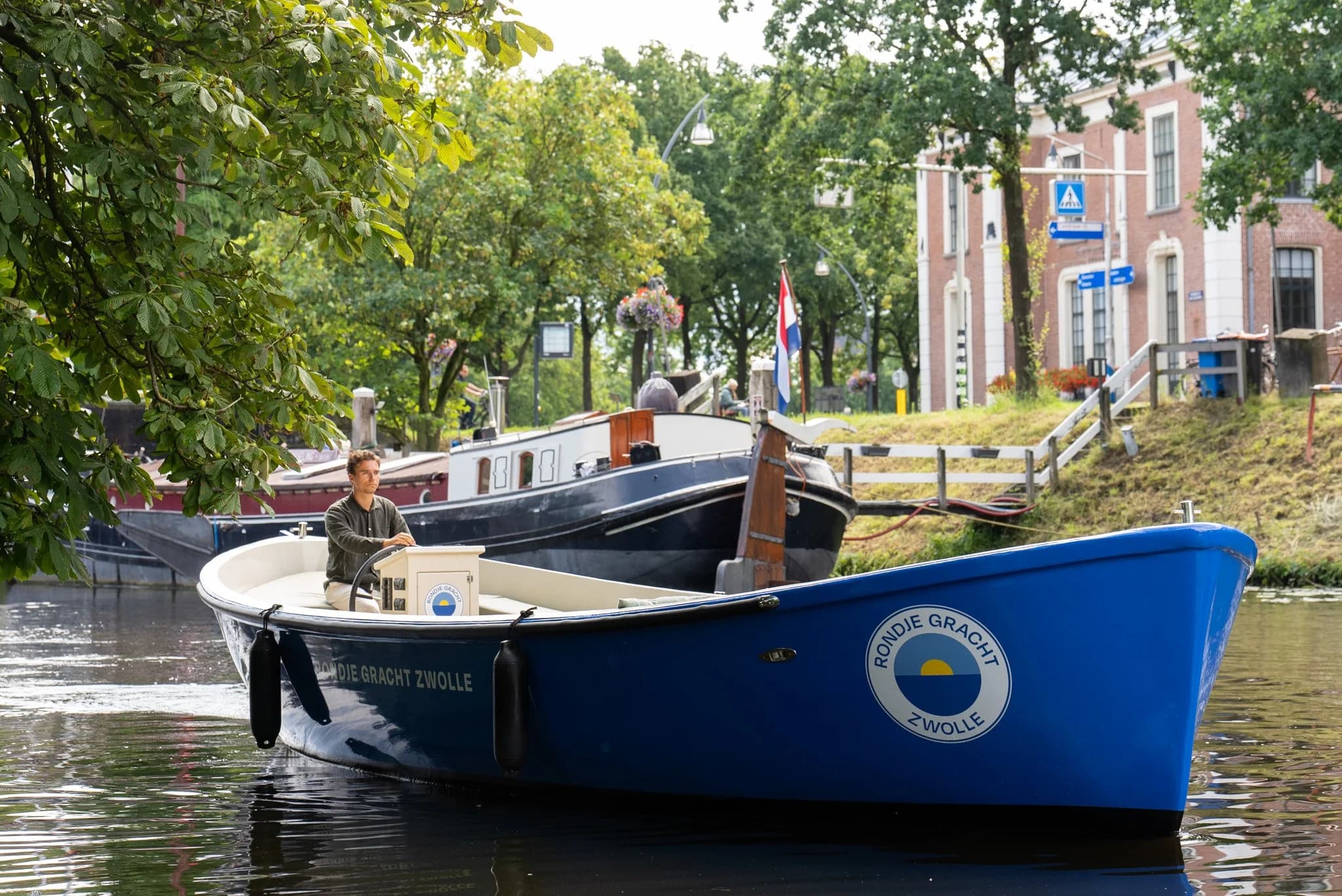 Die blaue Sloep Rondje Gracht Zwolle mit Skipper auf der Gracht in Zwolle